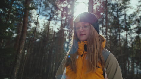 young woman hiking in forest on a sunny winter day