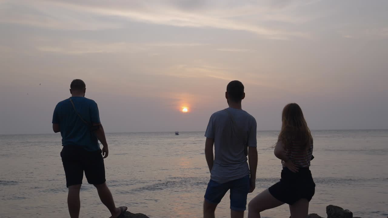 Group of friends admire sunset in Cartagena Colombia South America over sea water