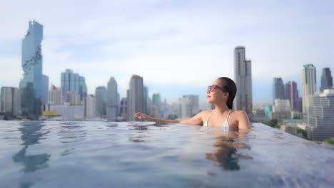 Mädchen-Im-Infinity-Pool,-Spa-Mit-Urbanem-Skyline-Hintergrund