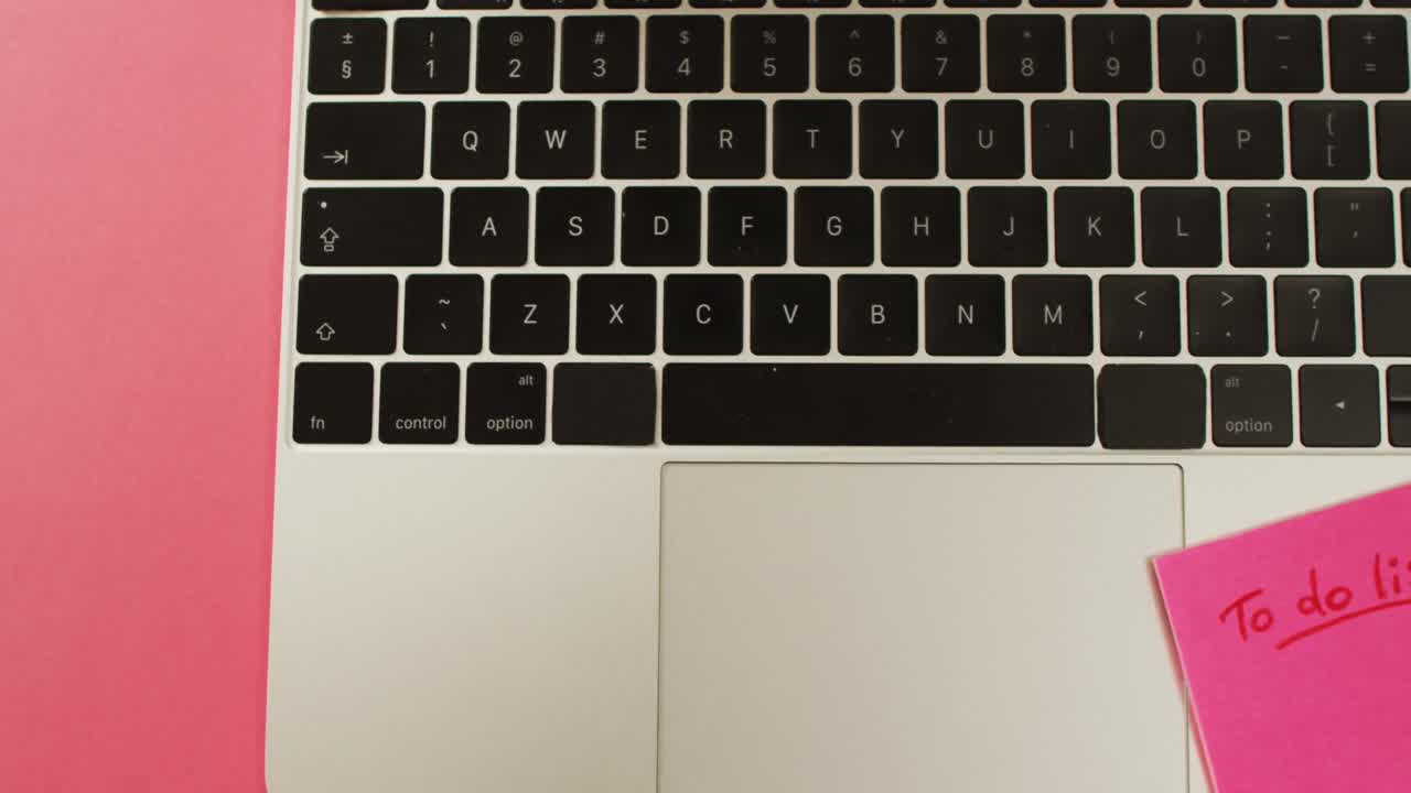 vídeo de una computadora portátil con una nota postal y un lápiz en la superficie roja