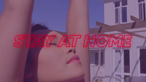 animation of colourful neon text stay at home over asian woman stretching