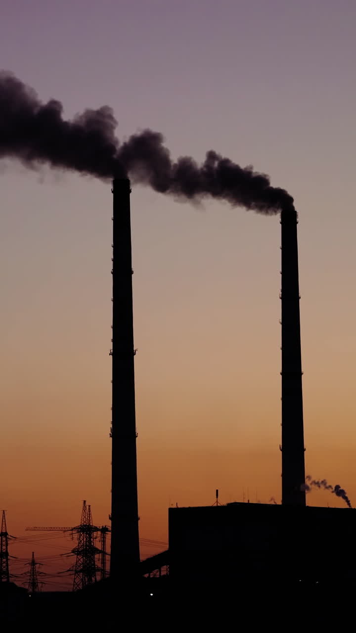 Dark smoke from pipes on the evening sky. Dirty emissions from pipes of industrial plant pollute the environment. Ecological problems. Vertical video