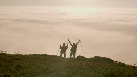 senior couple standing on top of mountain and raising arms up