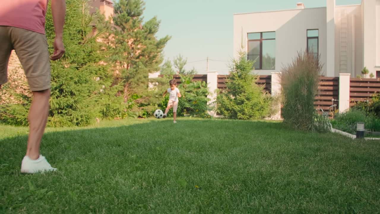 Father And Son Playing Football In Backyard