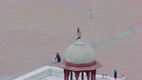 lahore, pakistán, minaretes de la mundialmente famosa mezquita badshahi vista aérea de cerca, visitantes damas, caballeros y niños están en la mezquita, fieles en el suelo de la mezquita, cometas negras