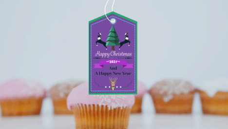 animación de felicitaciones de navidad en etiqueta sobre cupcakes en fondo blanco