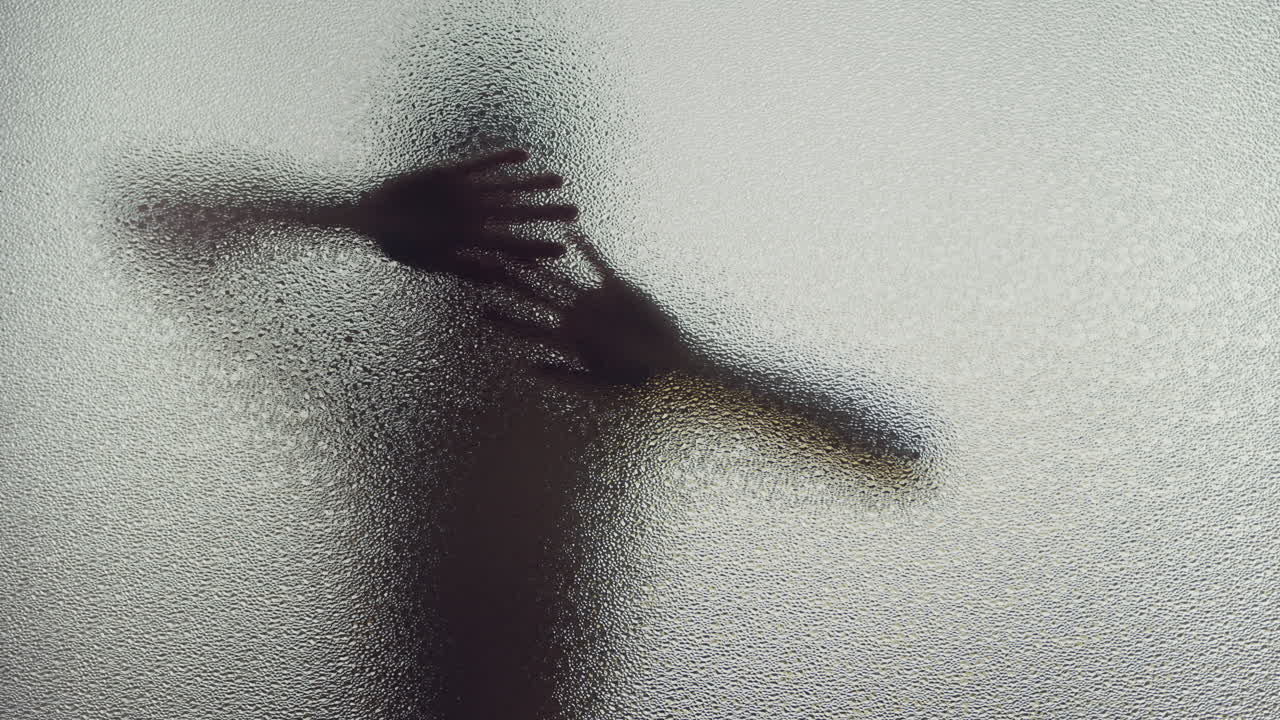 A female silhouette behind the frosted window dances slowly