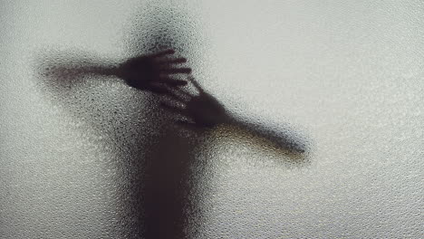 a female silhouette behind the frosted window dances slowly