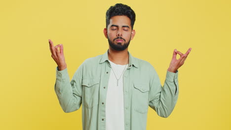 Indian-man-meditating-breathes-deeply-with-mudra-yoga-gesture,-eyes-closed,-taking-a-break,-relax