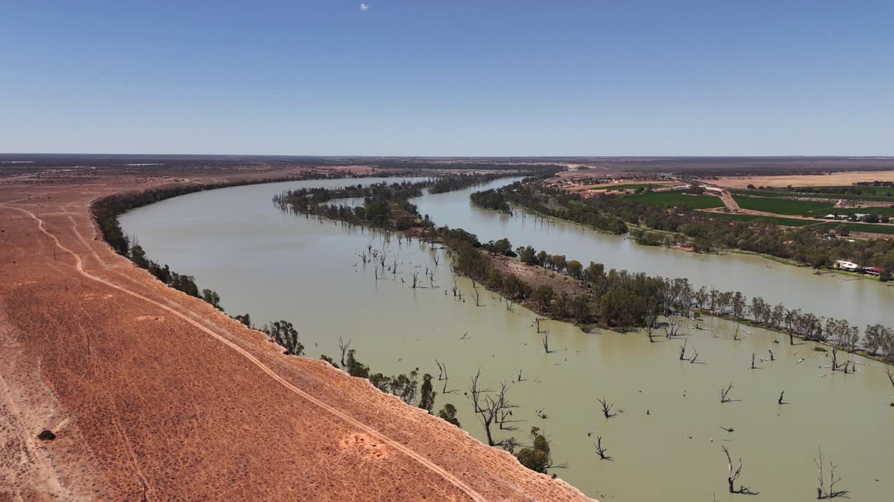 Drone che segue la curva del fiume accanto alla terra arida, mostrando un netto contrasto tra acqua e terra nell'entroterra australiano, Blanchetown, Adelaide, Australia