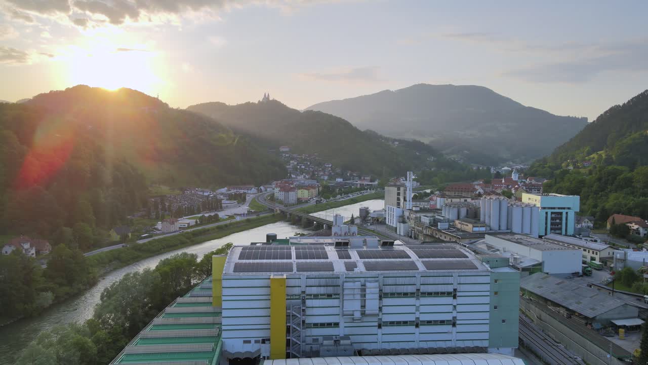 Aerial flyover Famous La&scaron;ko brewery in Lasko town in Slovenia during golden sunset behind mountain range