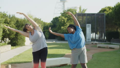 front view of cheerful friends bending to sides in summer park