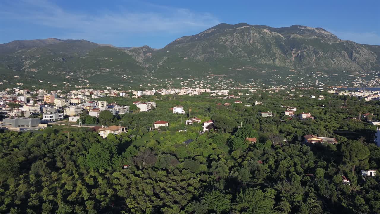 Aerial wide pan view of Taygetos Mountain View from Kalamata city, Peloponnesus, Greece on a sunny day, with olive tree forest in the foreground 4K