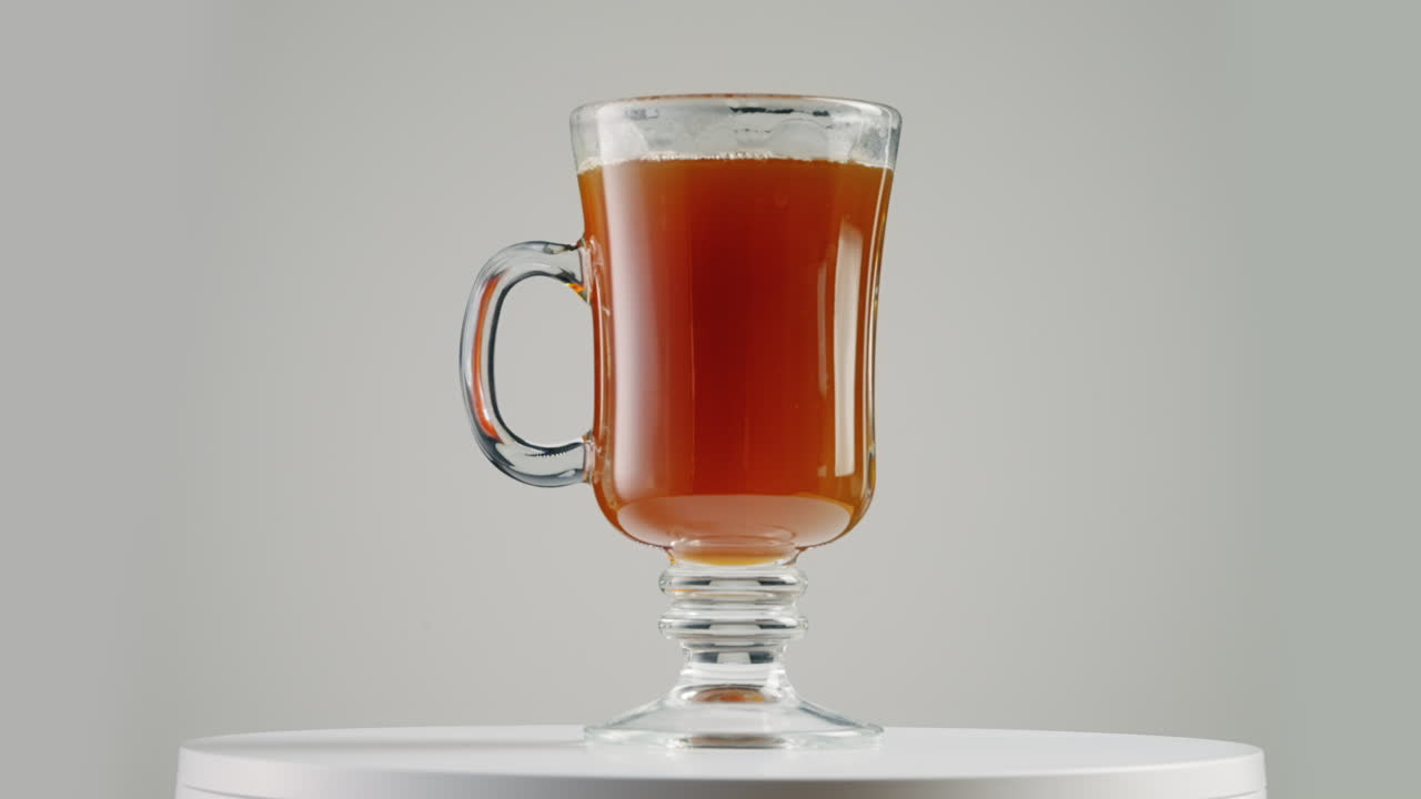 Studiobilde av roterende glasskaffekopp på dreieskive med hvit bakgrunn