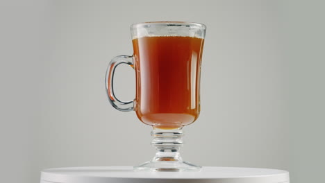 Studio-Shot-of-Spinning-Glass-Coffee-Cup-on-Turntable-with-White-Backdrop