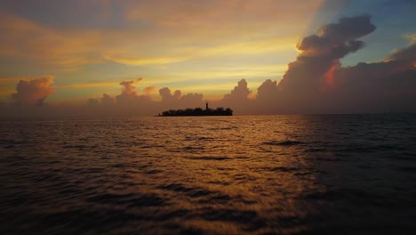 high speed cruising over the ocean with a tropical island in the back at sunrise