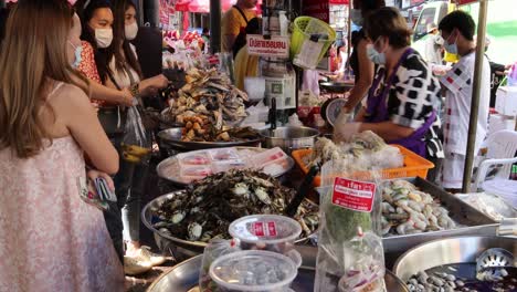 customers and vendors interact at seafood stall.