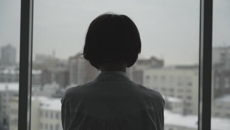 woman looking out of a window in a city