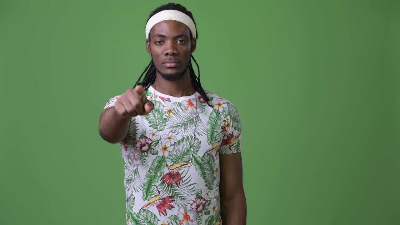 joven hombre africano guapo con dreadlocks contra un fondo verde