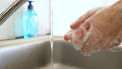 mujer caucásica lavándose las manos con jabón en casa
