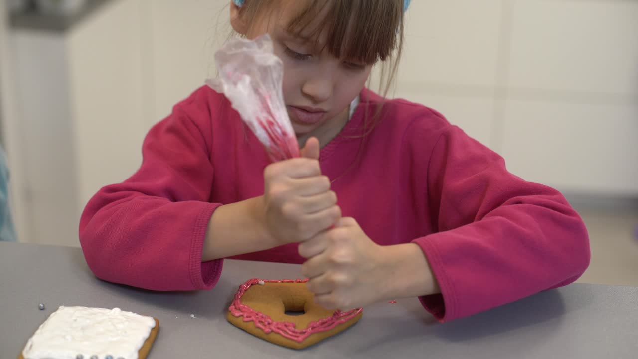 vista de cerca de las manos de los niños decorando galletas caseras para las vacaciones. un niño decora galletas presionando fondant o pasta de un tubo