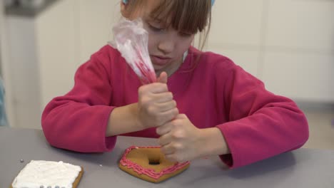 Nahaufnahme-Von-Kinderhänden,-Die-Selbstgemachte-Kekse-Für-Feiertage-Dekorieren.-Ein-Kind-Dekoriert-Kekse,-Indem-Es-Fondant-Oder-Paste-Aus-Einer-Tube-Auspresst