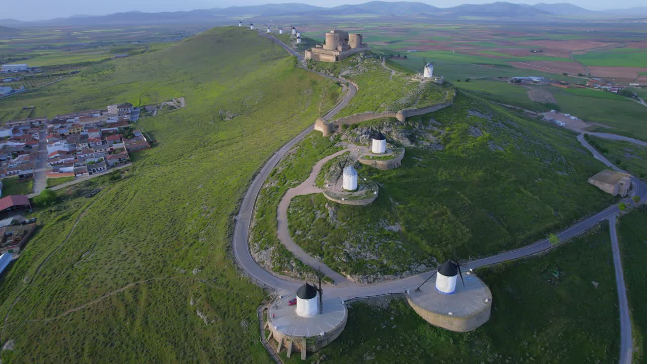 vista aérea panorámica de viejos molinos de viento y castillo en la cima de la colina al amanecer, turismo histórico español