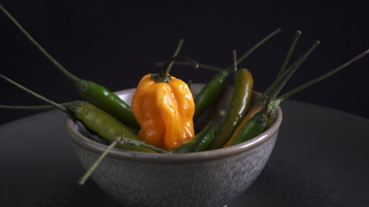 중앙에 신선한 캐롤라이나 리퍼가 있는 회전하는 칠리 고추가 가까이 있는 어두운 분위기