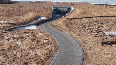 Front-view-of-modern-natural-building-incorporated-in-landscape-on-shore-of-lake,-VÃ¶k-Spa