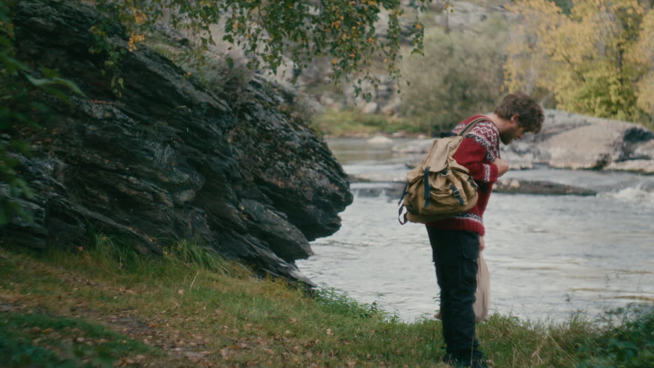 Tourist with Backpack Walking toward River and Enjoying Scenery