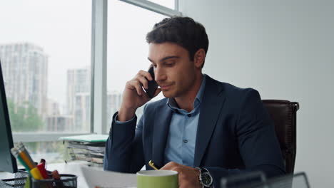 Nervous-manager-talking-mobile-phone-in-office.-Stressed-businessman-discussing