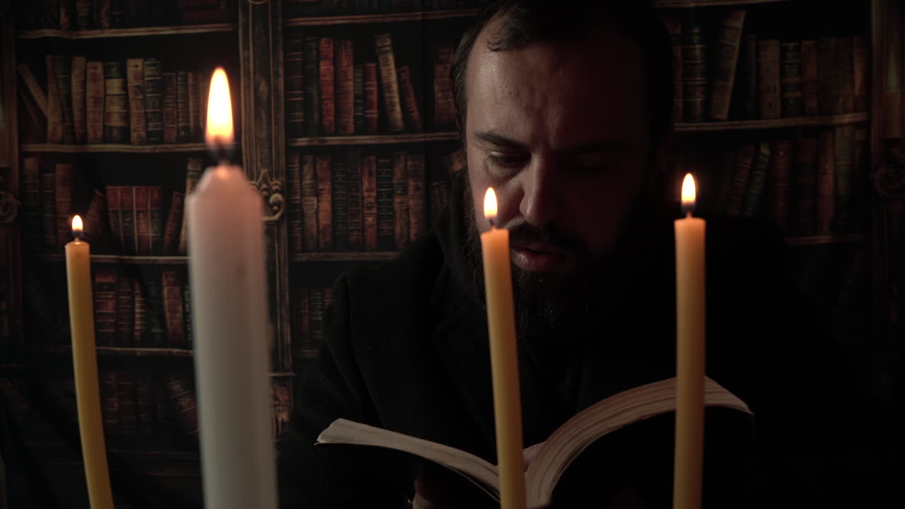 Uomo religioso che legge la Bibbia in una stanza buia davanti alla luce di una candela