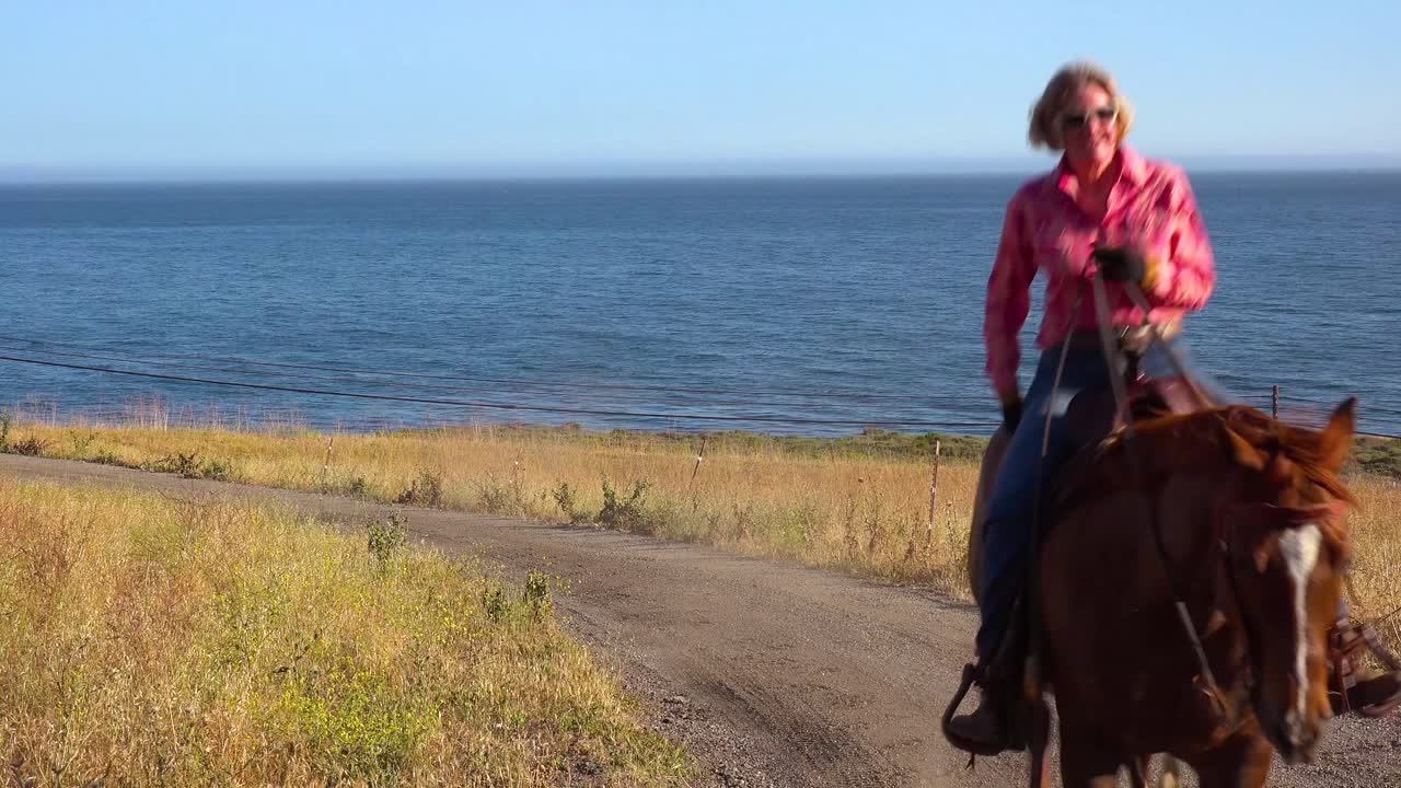 una mujer vaquera galopa en su caballo a lo largo del océano pacífico cerca de santa barbara california