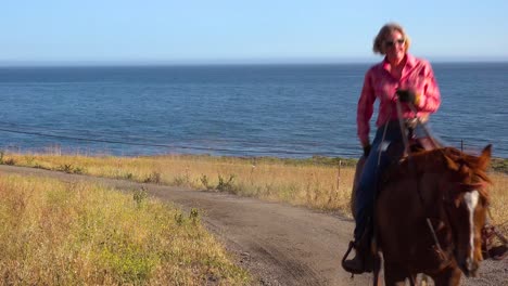 a woman cowgirl gallops on her horse along the pacific ocean near santa barbara california