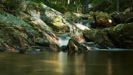 Mountain-stream-cascades-as-the-shadows-cross-the-ground---long-exposure-time-lapse