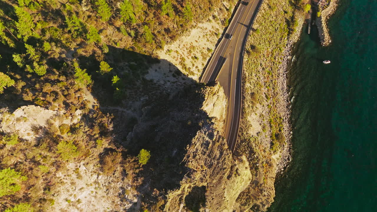 Rock with tunnels for cars movement on the highway. Drone footage over the road at the rocky shore of a Lake Tahoe, California, USA.