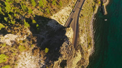 Rock with tunnels for cars movement on the highway. Drone footage over the road at the rocky shore of a Lake Tahoe, California, USA.