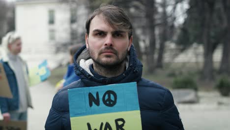 young caucasian man standing with manifest banner on cardboard.