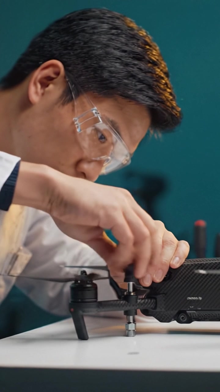 A focused technician carefully assembles and inspects a drone's rotor, showcasing precision engineering and attention to detail in technological innovation and repair.