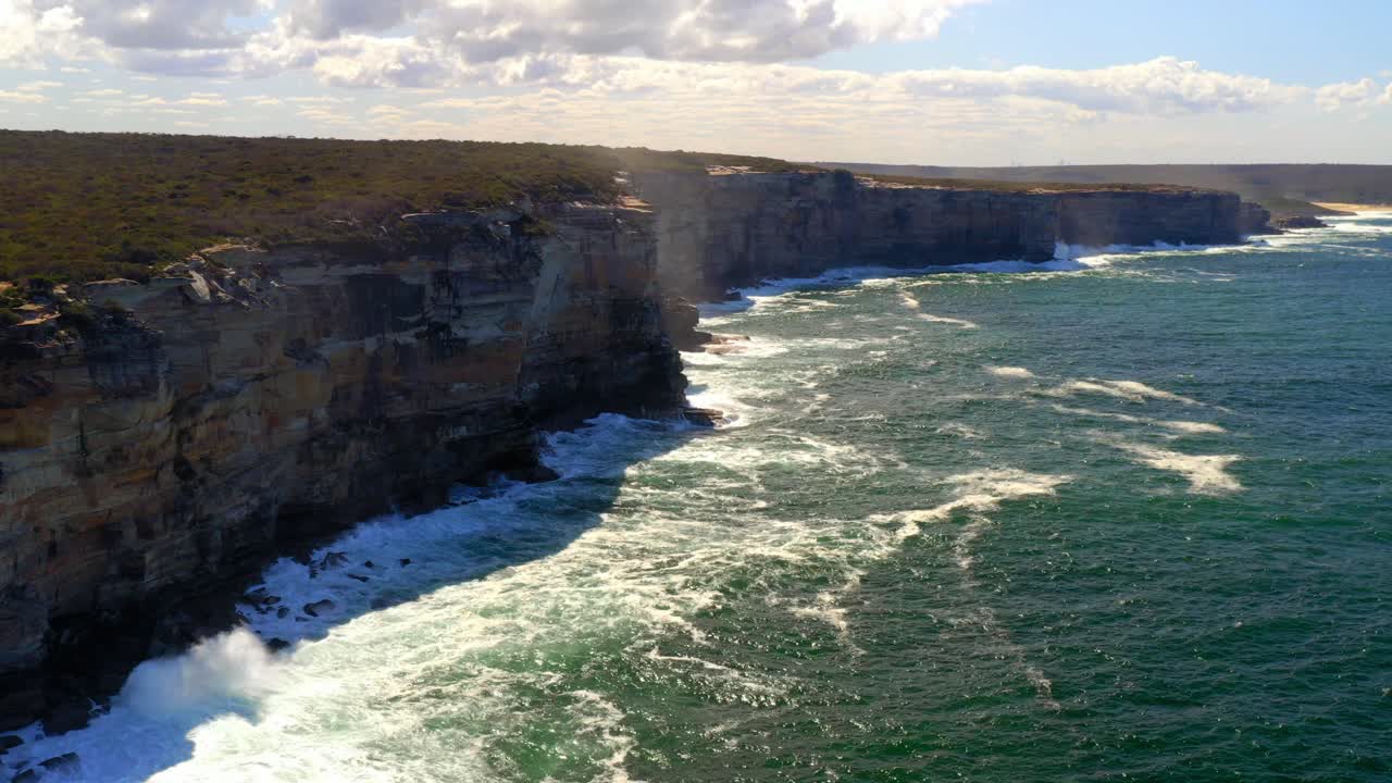 Waves Crashing Into Rugged Cliffs At Royal National Park In New South Wales, Australia - aerial drone shot