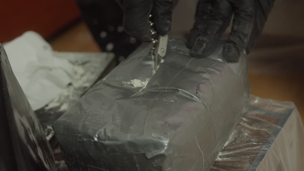 traficante de drogas cortando un paquete de sustancias ilegales