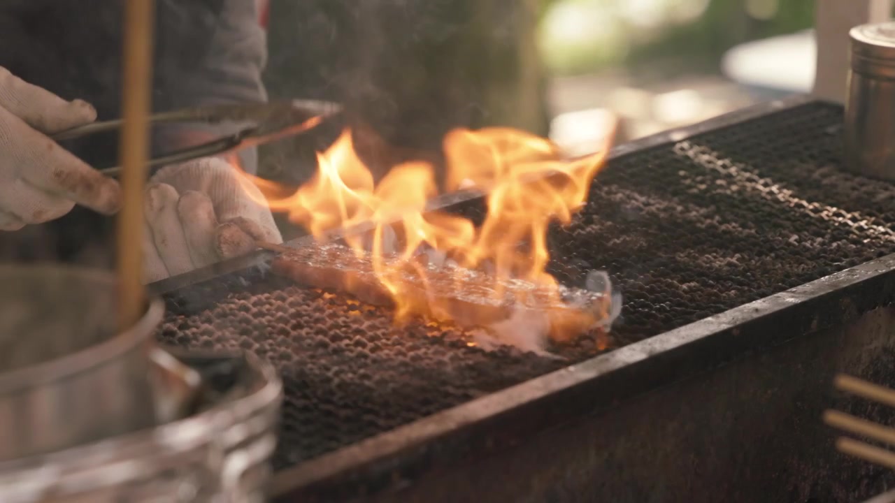 A Man Wearing Gloves Grills Meat Skewers At A Street Food Stall In Japan. Close-up Shot