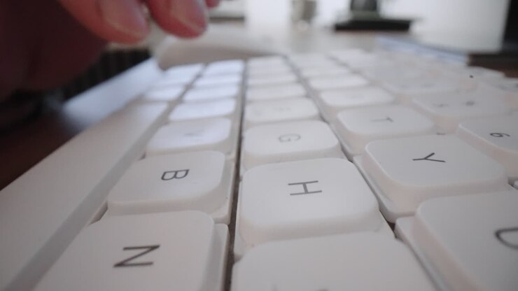 Close-up Moving Macro Shot: Man hands typing on laptop keyboard working on Internet project at light workplace. Online content. Digital marketing. Business intelligence. Digital analytics.