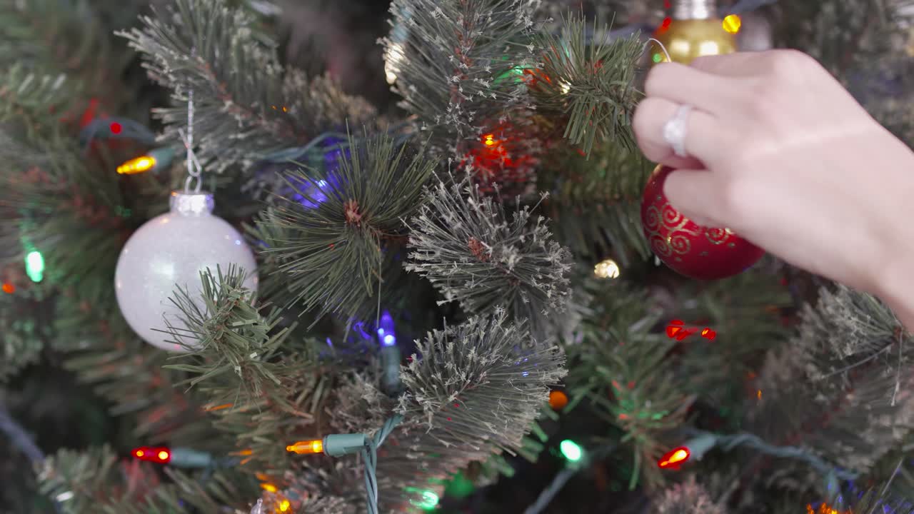 Hanging a Christmas ornament on Christmas tree