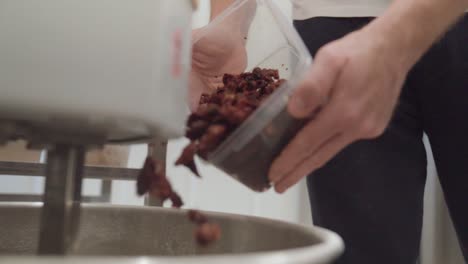 chef adding dried tomatoes into dough mixer