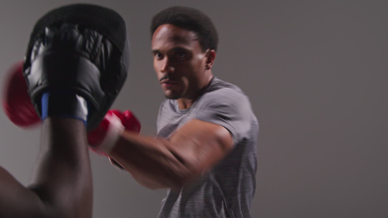 남자 권투 선수가 스파링을 하고 트레이너와 함께 치 손바닥이나 장갑을 착용하여 싸움을 위해 연습하는 스튜디오