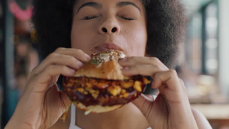 beautiful woman with afro eating burger in restaurant enjoying delicious juicy hamburger mouth watering meal african american female having lunch 4k