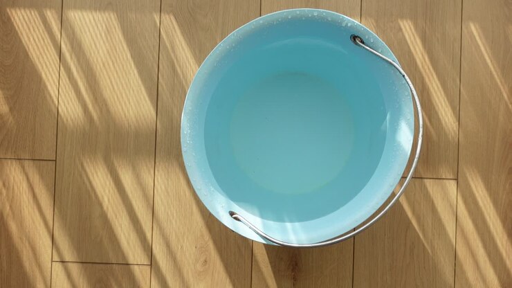 Blue bucket of water on a wooden floor