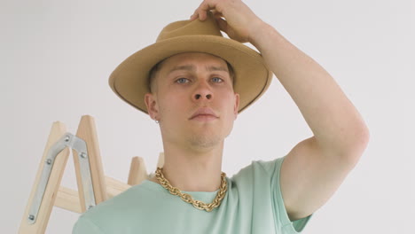 handsome man on a ladder, putting his hat on