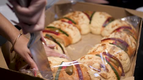 Latina-Woman-With-Long-Decorated-Nails-Clutching-A-Slice-Of-A-Rosca-De-Reyes-On-January-6-With-Her-Family-In-Mexico-Due-To-Three-Kings-Day-Celebration,-Traditional-Mexican-Bread